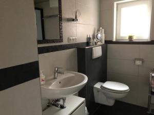 a bathroom with a sink and a toilet and a window at Neues Schwalbennest 26 Haus in Büsum