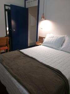 a bedroom with a large white bed and a blue door at A3EM Casa de Gorceix in Ouro Preto