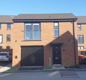 a red brick house with a black garage at 5 Star Luxury Small Cosy House with Lake View in Doncaster