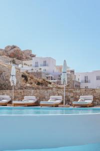 a swimming pool with lounge chairs and umbrellas at Arocaria Mykonos in Mikonos