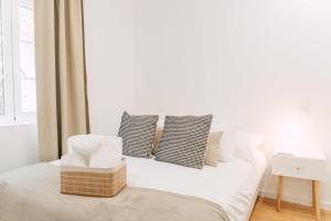 a white bedroom with a bed with pillows and a window at Oporto Yellow Villas in Porto