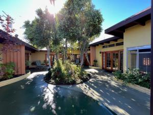 a courtyard of a house with a tree in the middle at Atrium Palm Springs - G A Y mens Resort in Palm Springs
