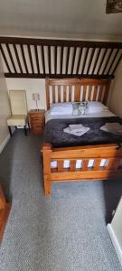 1 dormitorio con cama de madera y silla en The Stables at The George Of Wilby en Wellingborough