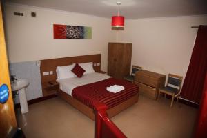 1 dormitorio con cama, lavamanos y manta roja en Grove Apartments, en Londres