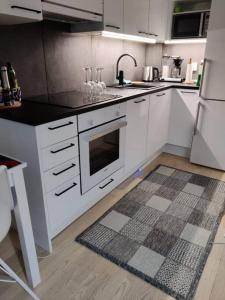 a kitchen with white appliances and a rug on the floor at Cozy studio in the city center in Rovaniemi