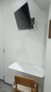 a tv hanging on a white wall with a table at Lapa Bed & Breakfast in Rio de Janeiro