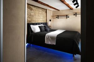 1 dormitorio con cama negra y pared de ladrillo en Pendino Luxury Rooms, en Nápoles