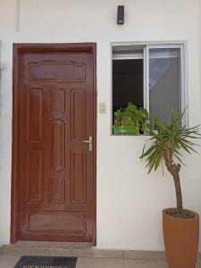 una porta marrone con una pianta in vaso davanti di Acogedor independiente-Casa JH A a Santa Cruz de la Sierra