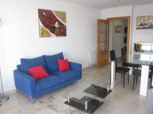 un soggiorno con divano blu e tavolo in vetro di Apartamento ideal a Guadix