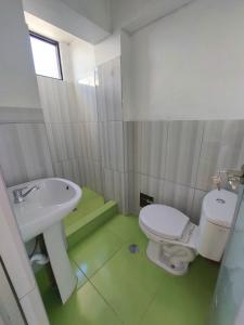 a bathroom with a white toilet and a sink at Disha's Home Casa Hospedaje in Ayacucho