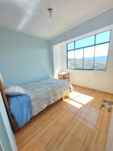 ein Schlafzimmer mit einem Bett und einem großen Fenster in der Unterkunft Disha's Home Casa Hospedaje in Ayacucho