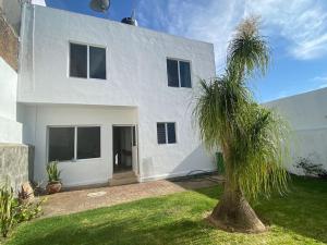 a white house with a palm tree in front of it at Casa en la naturaleza, Colima in Cuauhtémoc