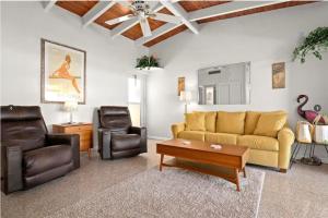 a living room with a yellow couch and leather chairs at Casa Mar by Beachside Management in Sarasota