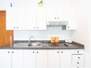 a kitchen with white cabinets and a sink at Weybeach2 -shared terrace,plaza view,sea frontline in La Santa