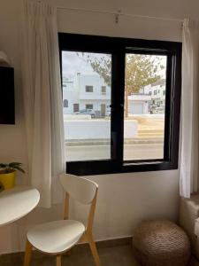 a white chair sitting in front of a window at Weybeach2 -shared terrace,plaza view,sea frontline in La Santa