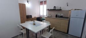 a kitchen with a white table and a white refrigerator at Elly Guest house in Alghero