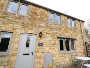 um edifício de tijolos com uma porta branca e uma mesa em Honeystone Cottage em Moreton-in-Marsh