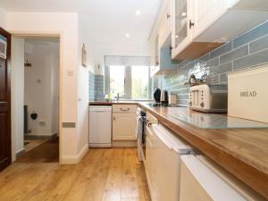 uma cozinha com armários brancos e um balcão de madeira em Honeystone Cottage em Moreton-in-Marsh