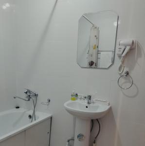 a white bathroom with a sink and a mirror at Phorto Bella in Ustʼ-Kamenogorsk