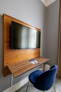 a flat screen tv on a wall with a blue chair at Hotell Hjalmar in Örebro