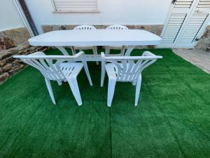 een witte tafel en stoelen op een groen gazon bij APPARTAMENTO LA CALETTA VACANZE in La Caletta