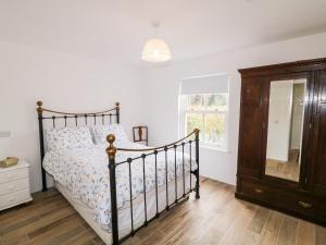 1 dormitorio con 1 cama, vestidor y ventana en The Poets Cottage, en Ballymena