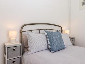 a bed with a blue pillow and two night stands at Lilyrose Cottage in Pevensey