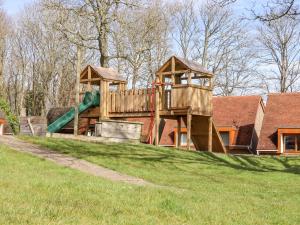 un parque infantil de madera con un tobogán en el césped en Lilyrose Cottage, en Pevensey