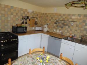 a kitchen with white cabinets and a black stove top oven at LE MYRO in Péreyres