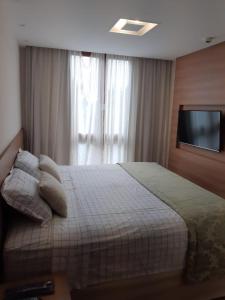 um quarto com uma cama e uma televisão na parede em Vista Azul Apart Hotel - Vista Pedra Azul com Cozinha Compacta em Domingos Martins