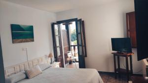 a bedroom with a bed and a tv and a window at Hotel Solatorre in Comillas