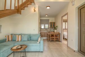 a living room with a blue couch and a table at Pink Sand Villas in Agios Padeleimon