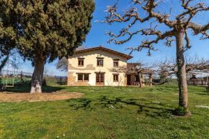 ein Haus auf einem Feld mit zwei Bäumen in der Unterkunft Can Salvà Casa rural en magnífico entorno natural in Girona