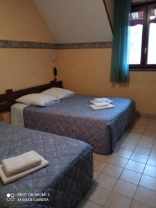 two beds in a hotel room with towels on them at Hôtel du tilleul in Corps