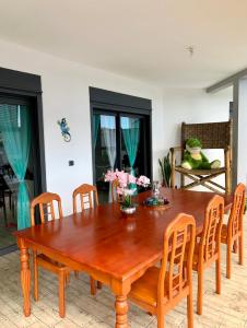 a dining room with a wooden table and chairs at la villa TIKALIKATA in Saint-Joseph
