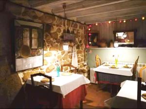 comedor con 2 mesas y pared de piedra en Casa Rural La Posada del Alba, en Alea