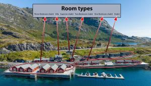 two boats are docked in the water near a mountain at Lofoten Cabins - Kåkern in Ramberg