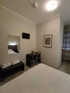 Cette chambre comprend un lit, une table et un miroir. dans l'établissement Hotel Salus, à Milan