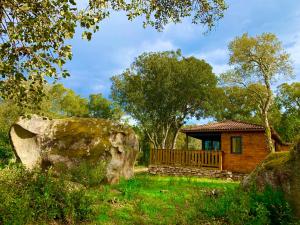 una cabaña de madera con una gran roca en el patio en L'Aravone Lodge, en Sartène