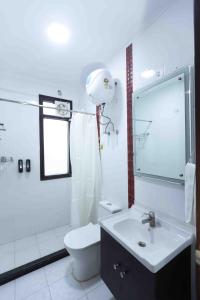 a white bathroom with a toilet and a sink at Plaza Residency in Gurgaon