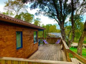 um deque de madeira com duas cadeiras e uma casa em L'Aravone Lodge em Sartène