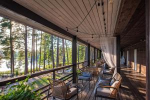 een afgeschermde veranda met stoelen, tafels en bomen bij Saarjärve Puhkemaja 16-le 4 magamistuba in Tromsi