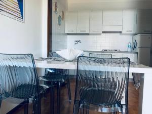 a kitchen with three chairs and a white counter at Luna 4 - 176 in Lignano Sabbiadoro