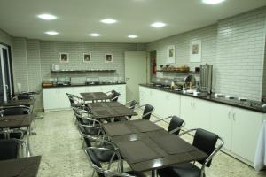 a dining room with tables and chairs and a kitchen at Hotel Confiance Soho Batel in Curitiba