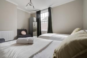 a white bedroom with two beds and a window at Rodney Street Luxury Townhouse & Apartments, Central & Stylish in Liverpool