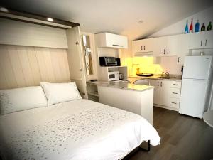 Il comprend une petite chambre avec un lit blanc et une cuisine. dans l'établissement Domaine Gagnon, à Saint-Sébastien