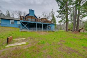 a blue house with a large deck in a yard at Mudge Ranch Retreat near Bass Lake with EV Charger in Coarsegold