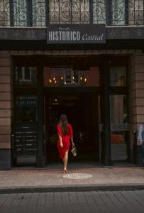 Una mujer con un vestido rojo caminando delante de una tienda en Historico Central Hotel en Ciudad de México