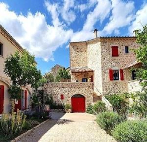 duży kamienny budynek z czerwonymi drzwiami w obiekcie clos de Beauregard w mieście Joyeuse