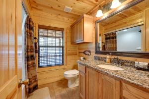 a bathroom with a toilet sink and a mirror at Broken Bow Cabin with Hot Tub and Deck - 4 Mi to Lake! in Broken Bow +25 photos